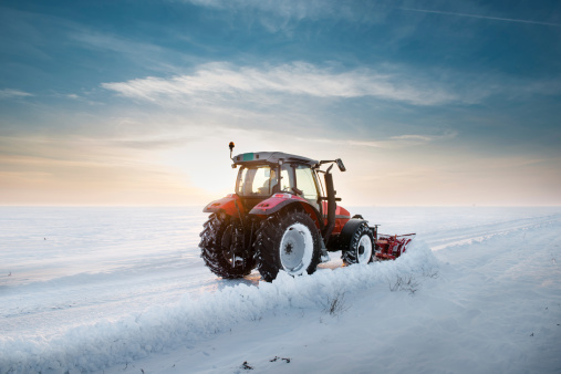 Tractor cleaning snow in sunset