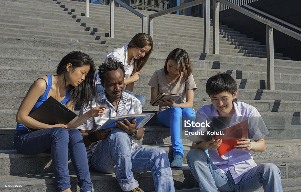 Multiétnico Grupo de estudantes universitários sentado nas escadas - Foto de stock de Adulto royalty-free