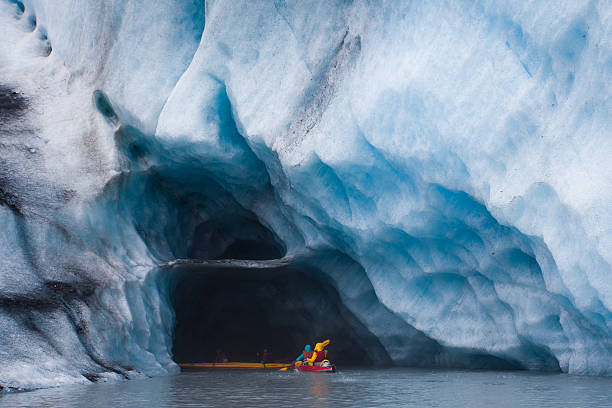 Kayaking into blue ice cave stock photo