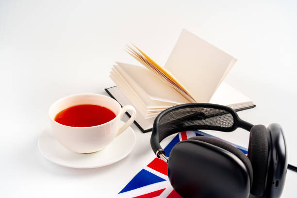 blocco note con bandiera britannica e cuffie su sfondo bianco. concetto educativo di audiocorsi in lingua inglese - british culture audio foto e immagini stock
