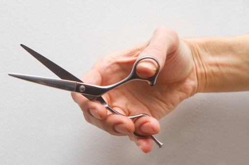 A hairstylist's hand holding scissors.