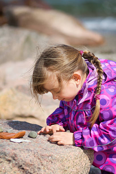 istock Girl Examining Beach Pebble 178556429