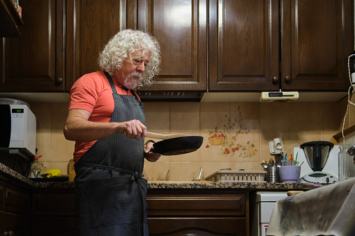 side view portrait of a retired old white man preparing some food at home