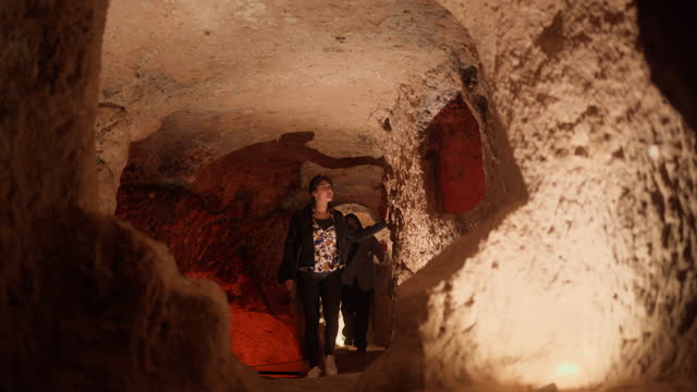 Two female tourist friends visiting underground city in Cappadocia Türkiye Turkey during their travel