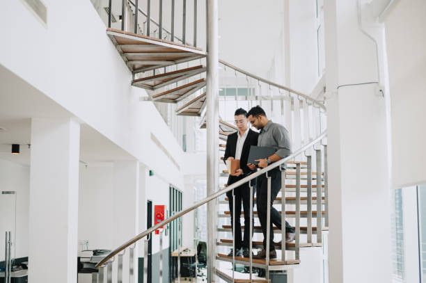 istock Two Asian businessmen talking in office stairs. 1785598158