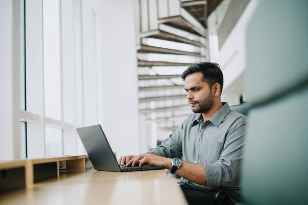 istock Handsome Asian Indian businessman working alone in office. 1785599825