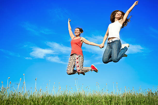 Two happiness young women jumping over blue sky