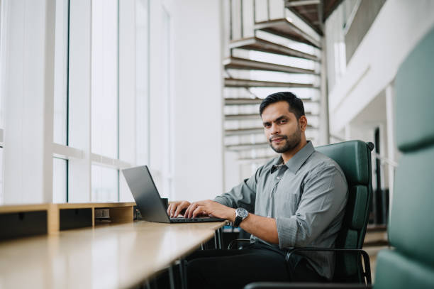 istock Handsome Asian Indian businessman working alone in office. 1785602936