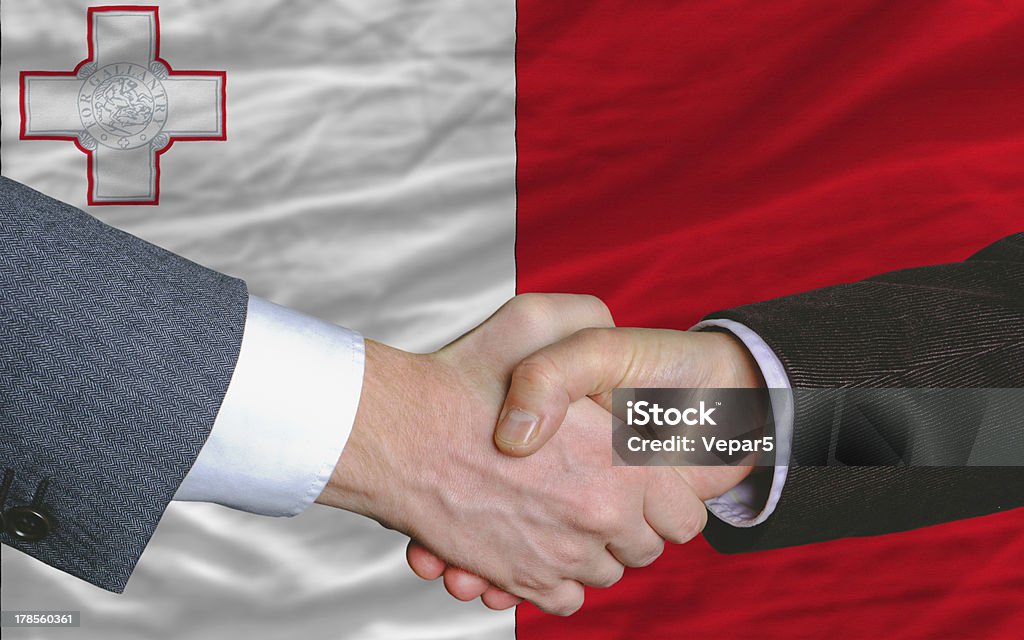 businessmen handshake after good deal in front of malta flag two businessmen shaking hands after good business investment  agreement in malta, in front of flag Agreement Stock Photo