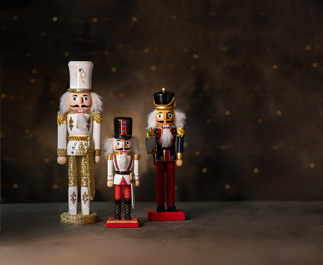 Nutcrackers on a glass table with out of focus christmas lights in the background.