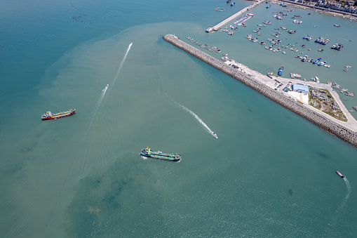 Aerial view of fishing boats entering and exiting the fishing port in the fishing village