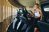 Happy female athlete adjusting speed on treadmill in a gym.