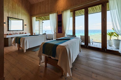 Modern spa room with massage tables and sea view through the window.