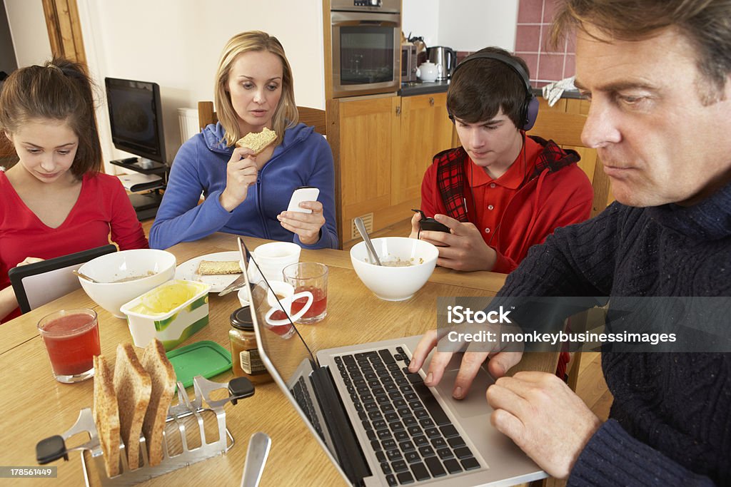 Adolescente usando Gadgets mientras que la familia comiendo juntos en cocina, desayuno - Foto de stock de Distraerse libre de derechos