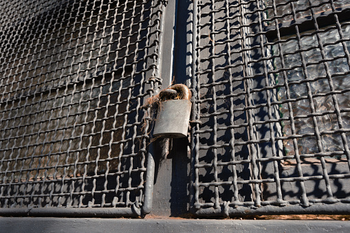 Low angle view of a padlock on an old metal gate.