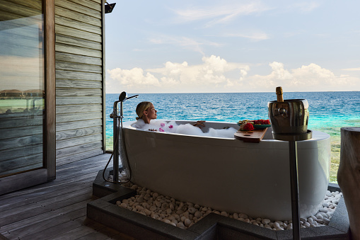 Carefree woman spending a summer day in a hot tub in a tourist resort by the sea. Copy space.