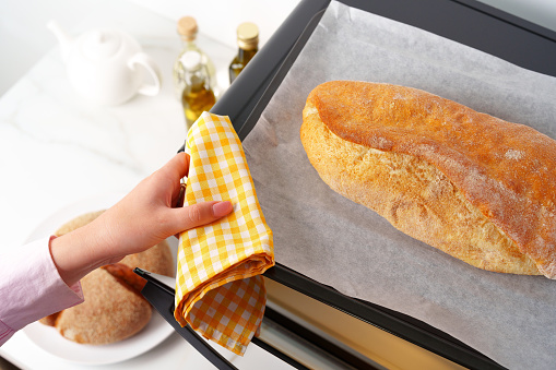 Woman's hands taking fresh bakery out of mini oven close up