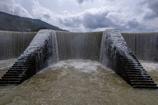 A close-up of a dam overflowing a reservoir with floods