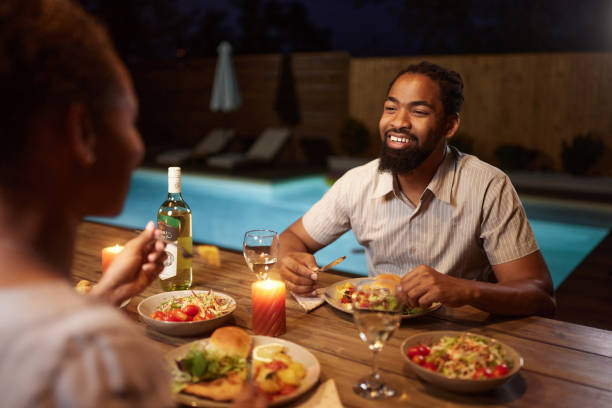 istock Happy black couple talking during dinner on a patio by the pool. 1785646301