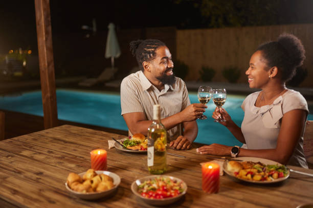istock Happy black couple toasting during dinner on a patio by the pool. 1785646824
