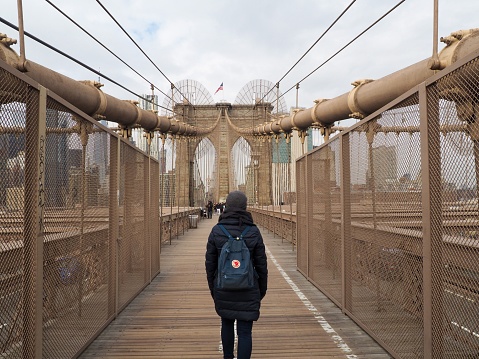 New York, United States – February 14, 2020: A female traveler standing on the Brooklyn Bridge
admiring the scenic view in the United States