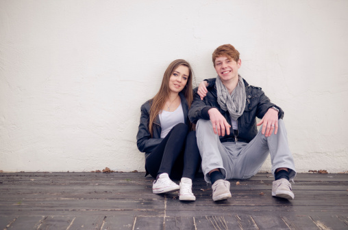 Teenage couple sitting by the wall