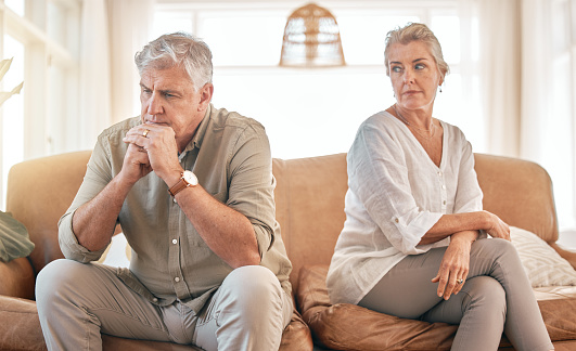 Senior couple, divorce and disagreement in conflict, fight or argument on living room sofa at home. Elderly woman and frustrated man in depression, cheating affair or toxic relationship in the house