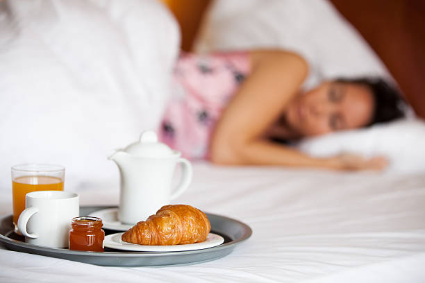 frau schläft im hotelbett und frühstück steht bereit - alleine fotografías e imágenes de stock