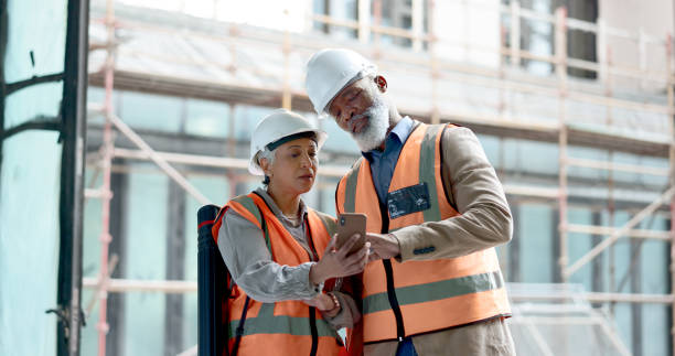 istock Construction, teamwork and talking with phone at building, architecture site and maintenance app. Man, woman and civil engineering collaboration on mobile tech, industrial project or urban inspection 1785677324