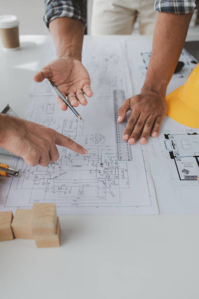 The home design architects are reviewing the house plan draft, the project commissioned by the client, and the custom design before delivery. Interior design and decoration ideas.