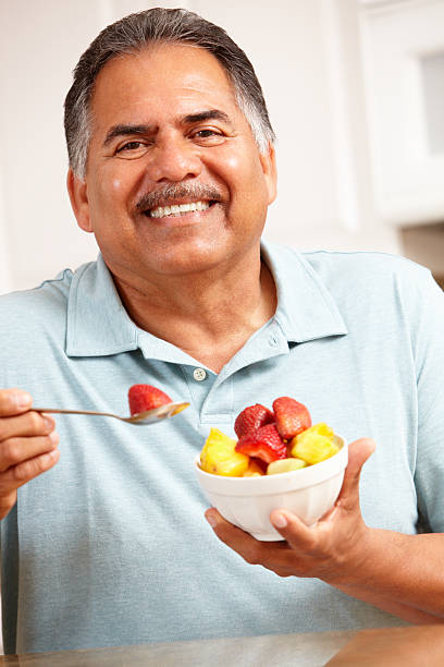 mangia frutta senior uomo - 60s senior adult breakfast cheerful foto e immagini stock