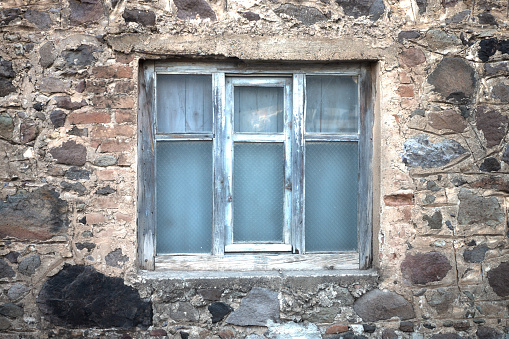 Window with yellow shutters on the facade of an old wooden cottage