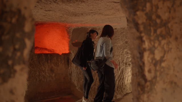 Two female tourist friends visiting underground city in Cappadocia Türkiye Turkey during their travel