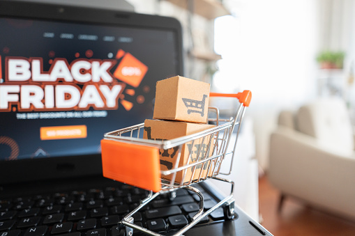 Miniature shopping cart and boxes stand on laptop , black friday concept