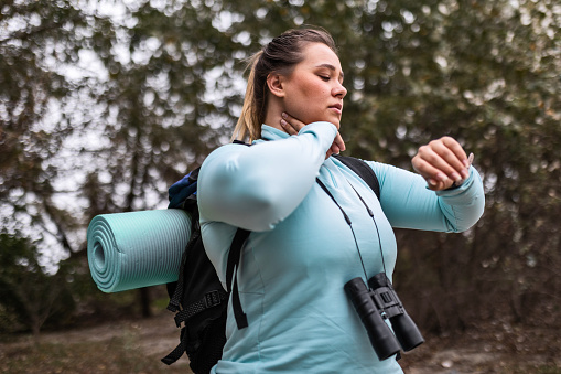 Hiker female in wood area measuring pulse looking at smart watch