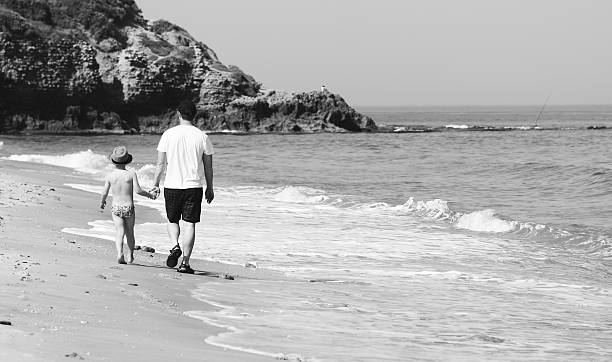 istock father and son walking together on the beach 178575090