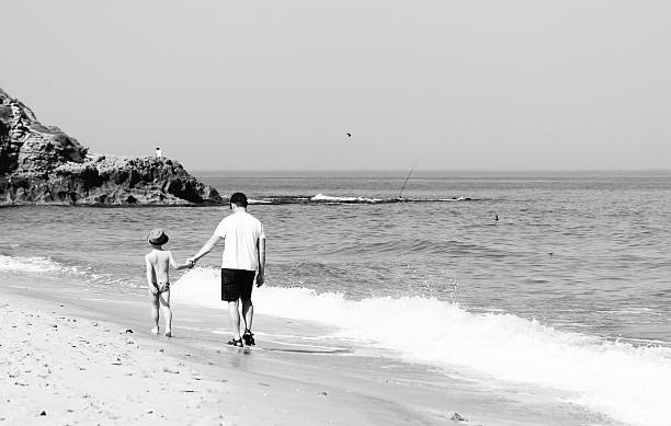 istock father and son walking together on the beach 178575632