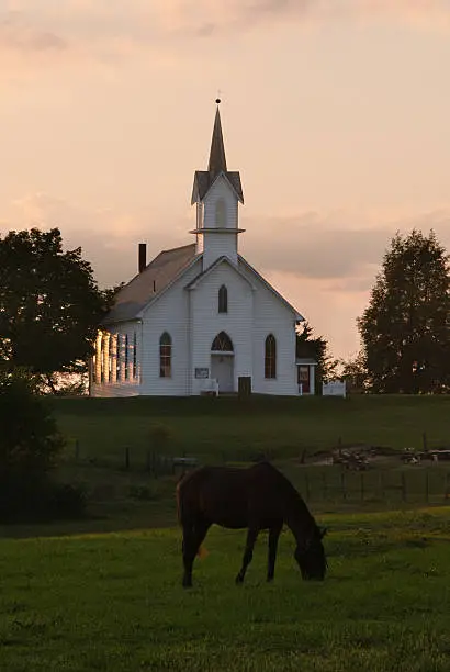 Amish church at twilight with horse grazing in the pasture out front.