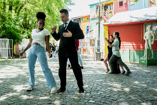 Street artist man teaching tango to tourist on Caminito, Buenos Aires, Argentina