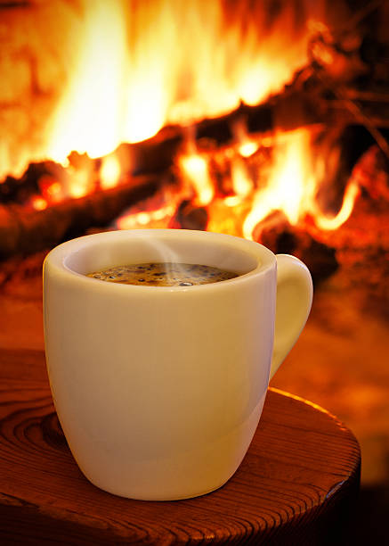 Cup of hot coffee in front the fireplace stock photo