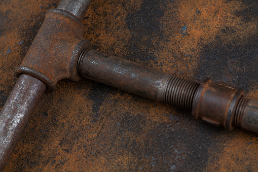 Rusty plumb tube on rusty metal wall background