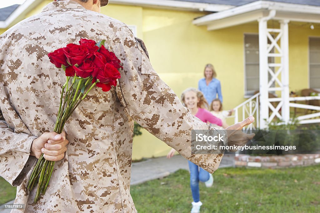 Family Welcoming Husband Home On Army Leave Family Running Out Of House Welcoming Husband Home On Army Leave 30-39 Years Stock Photo