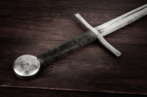 Medieval vintage sword on wooden background.