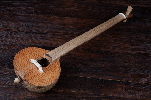 Turkish tambur. Long-necked folk string instrument of the lute family on wooden table.