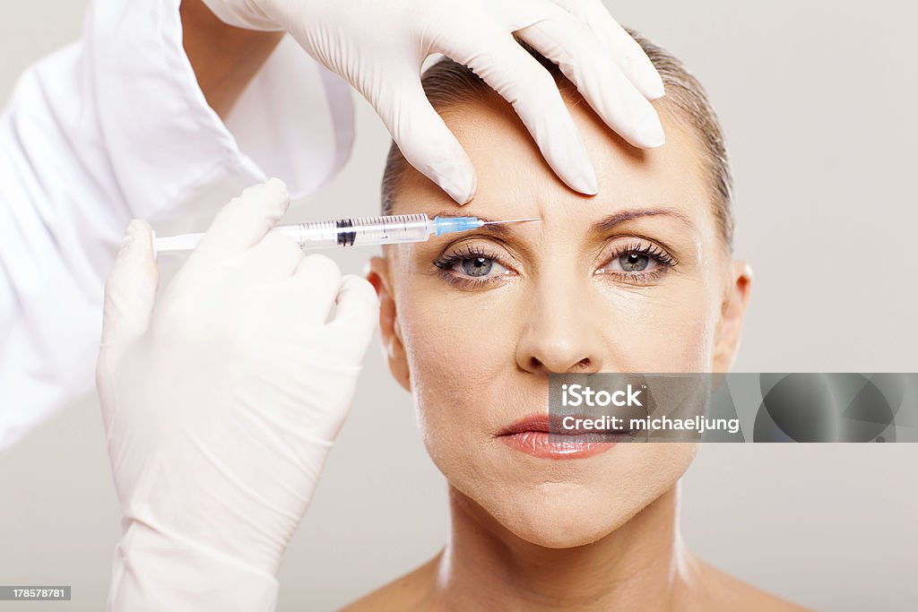 cosmetic surgeon giving face lifting injection cosmetic surgeon giving face lifting injection to mature woman 50-59 Years Stock Photo