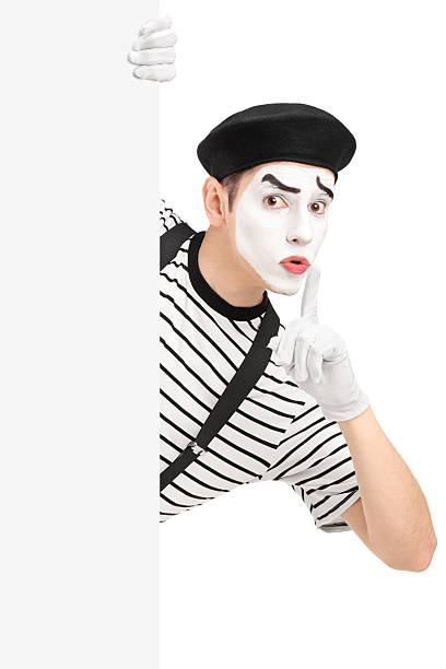 Male mime artist holding a panel and gesturing silence Male mime artist holding a blank panel and gesturing silence with a finger on his mouth, isolated on white background pantomime stock pictures, royalty-free photos & images