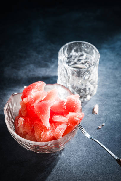 Sunlight shining on grapefruits with red flesh placed on a slate board in a bowl