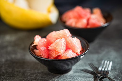 Sunlight shining on grapefruits with red flesh placed on a slate board in a bowl