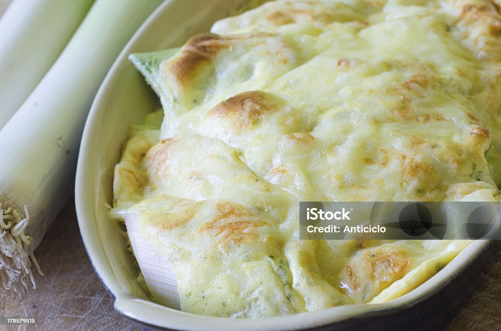 Leek gratin with quark and potatoes Close view of a dish of leek gratin with baked potatoes, ingredients on the background Gratin Stock Photo