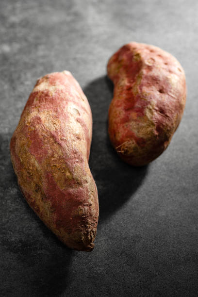 Old sweet potatoes placed on a black slate board.